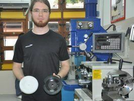 O estudante Gabriel Sanches, 22, mostra a peça manopla branca, construída para substituir a que estava quebrada (a de cor preta), da máquina fresa do Curso de Física